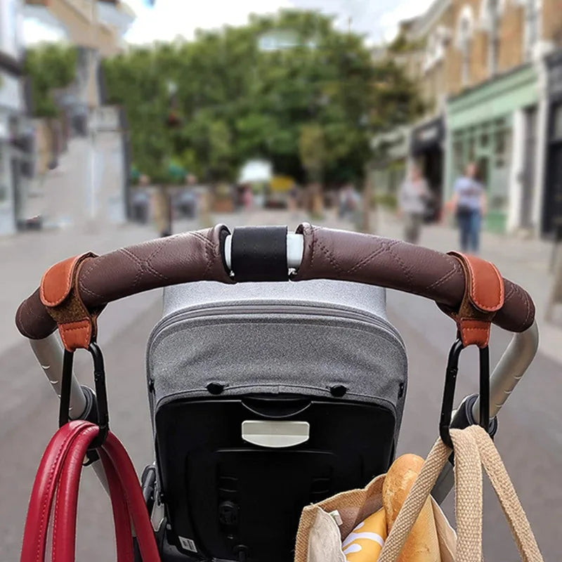 Stroller hooks in use on a pram handle outdoors