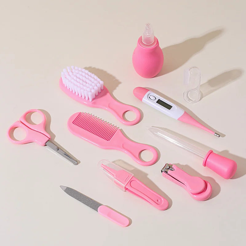 Baby grooming kit pieces laid out: brush, comb, thermometer, aspirator, dropper, clipper, file, tweezers, scissors and finger toothbrush
